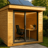 Een houten tuinhuis of blokhut als tuinkantoor. Er liggen zonnepanelen op het dak en er is een werkplek zichtbaar in het tuinhuis.