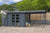 Afbeelding van een donkergrijs houten tuinhuis genaamd 'Dellinger' met afmetingen 298 x 298 x 225 cm en een luifel van 300 cm. De luifel wordt ondersteund door twee metalen palen. Het geheel staat op een bestrating van grote, bruin-grijze tegels. Op de voorgrond staan enkele planten in terracotta potten.