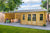 Houten tuinhuis Kwaspa 400 x 400 x 299 cm met een overdekt terras en een jacuzzi. Het tuinhuis heeft een houten gevel en een donker gekleurd dak.