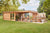 Een houten tuinhuis Casper (490x400x236cm) met een ruim overdekt terras en een hottub. Het tuinhuis staat in een groene omgeving en is omgeven door bomen. Mensen genieten van de buitenlucht op het terras.